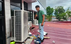 Teknisi Salman Teknik sedang melakukan perbaikan pada unit kondensor air conditioner (AC) di sela aktivitas nya